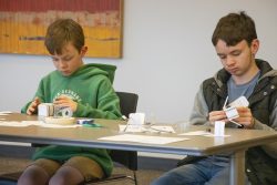 Two male students working intently on constructing a chain of circuit cubes."